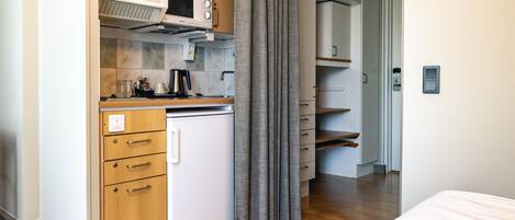 A compact kitchenette with a microwave, a small refrigerator, and a coffee maker.