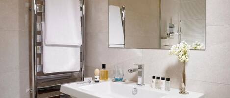 A modern bathroom with a white sink, chrome towel rack, and a mirror.