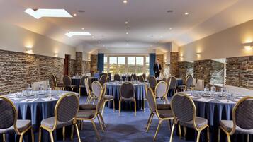 A conference room with round tables, chairs, and a view of a lake.