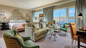 A hotel room with a bed, a sofa, a chair, a coffee table, and a view of the sea. - Trident Hotel (Kinsale)