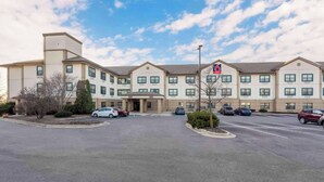 A multi-story hotel with a parking lot and a clear sky. - Studio 6 Corporate Extended Stay Chicago Lisle IL (Lisle)