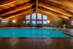 An indoor swimming pool with a wooden ceiling and large windows. - AmericInn by Wyndham Eau Claire (Eau Claire)