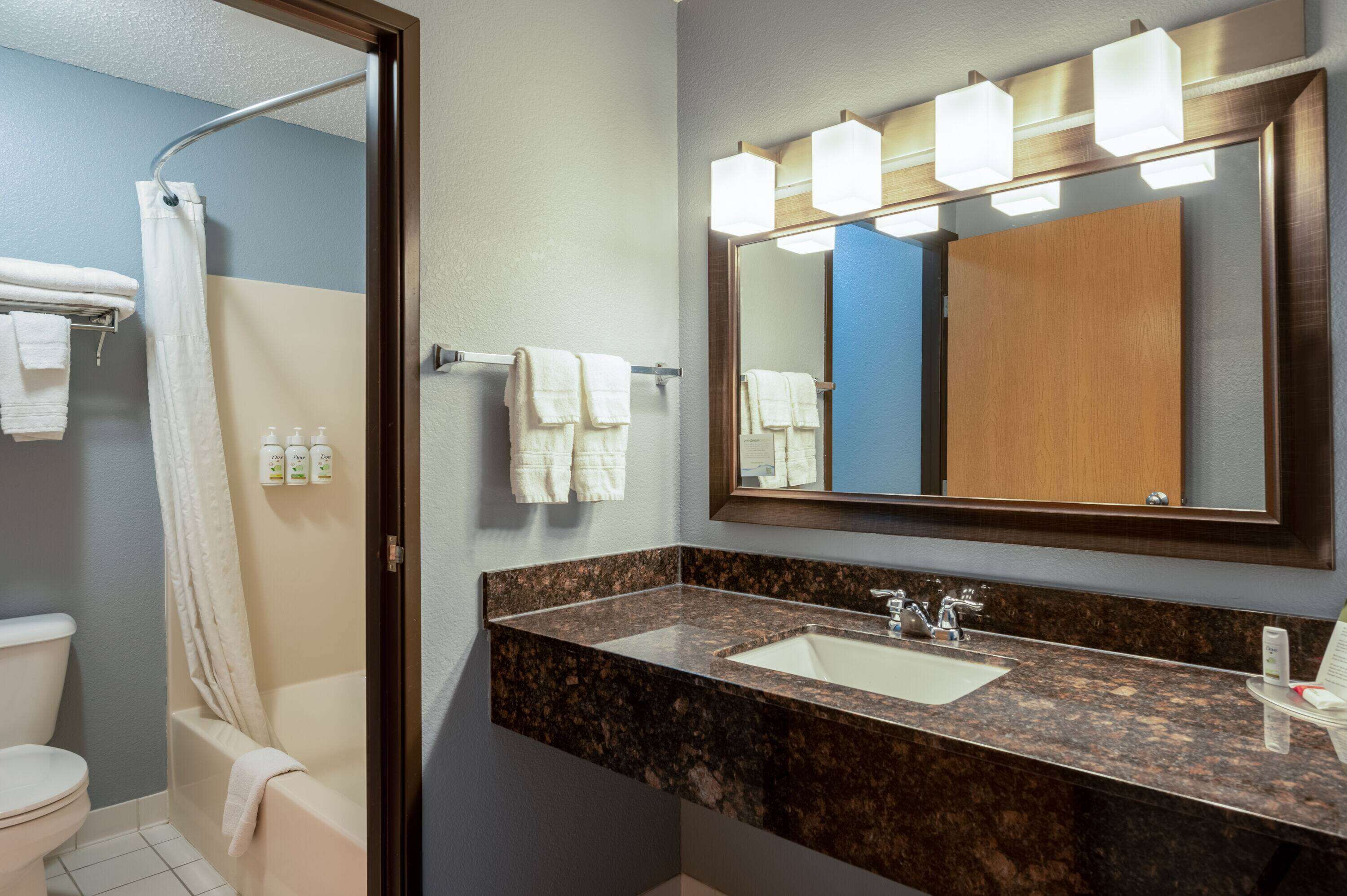 A bathroom with a marble sink, a large mirror, and a shower curtain.