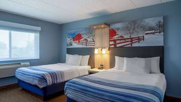 A hotel room with two beds, a large window, and a painting of a snowy farm scene.