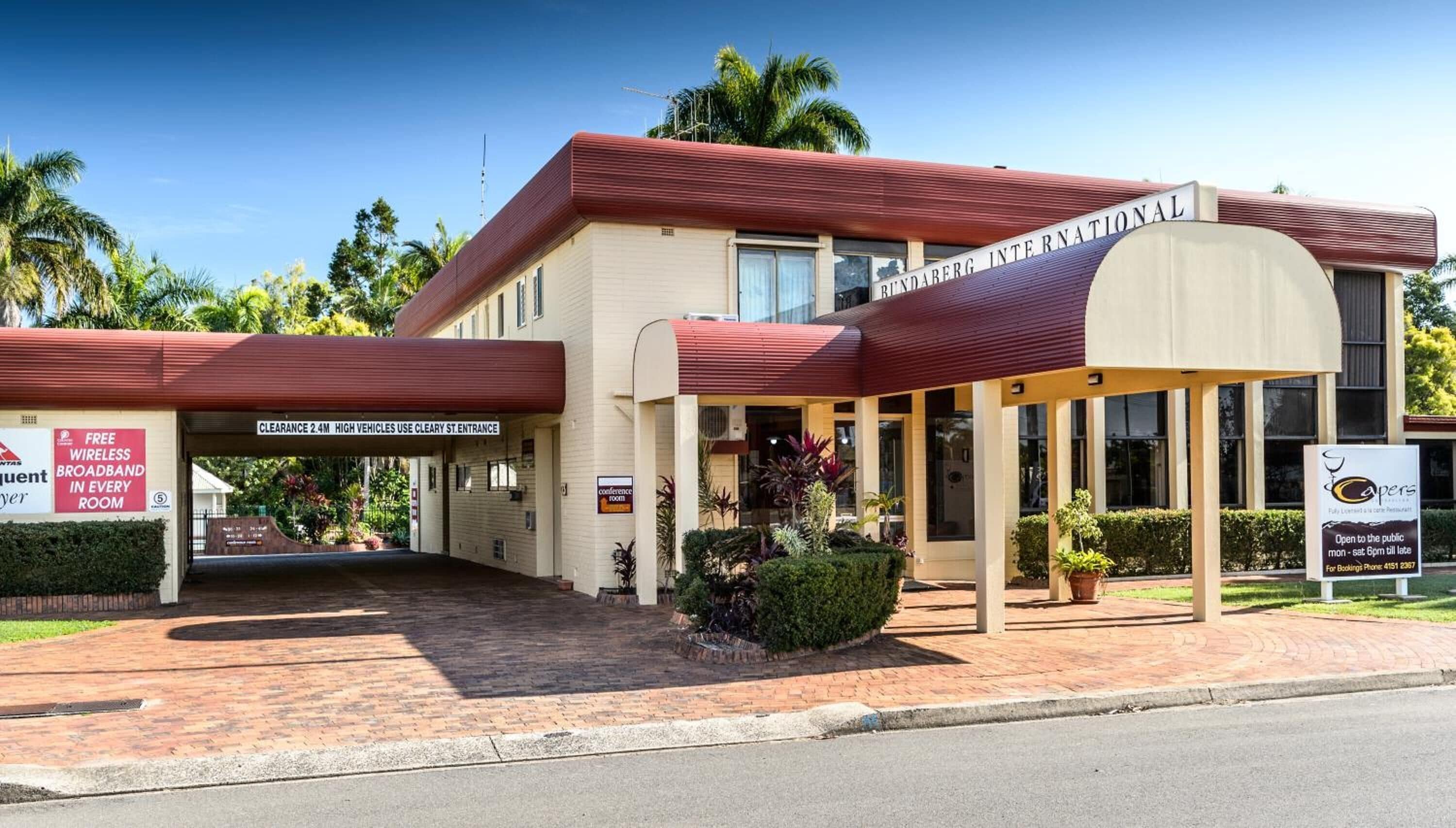 A hotel with a red roof, a covered entrance, and signs indicating free wireless broadband and a conference room.