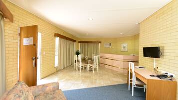 A hotel room with a dining area, a TV, and a desk.