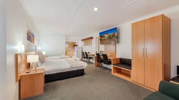 A hotel room with a bed, desk, chairs, and a TV.