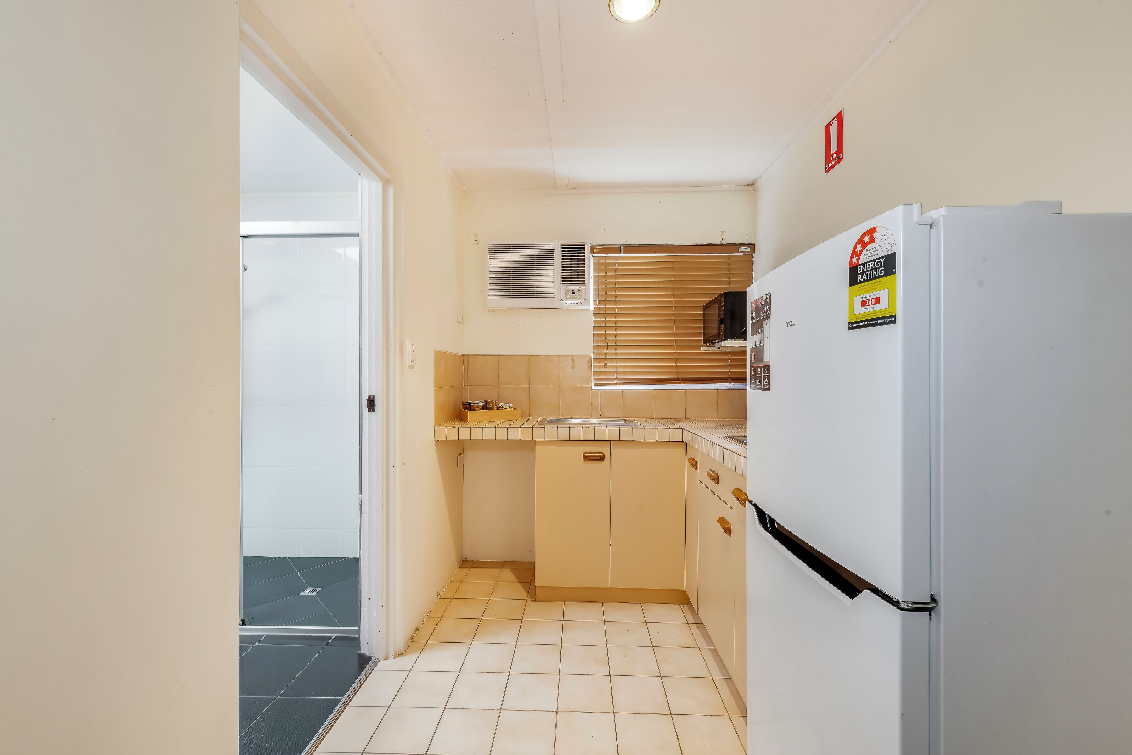 A compact kitchen with a refrigerator, a microwave, and a sink.