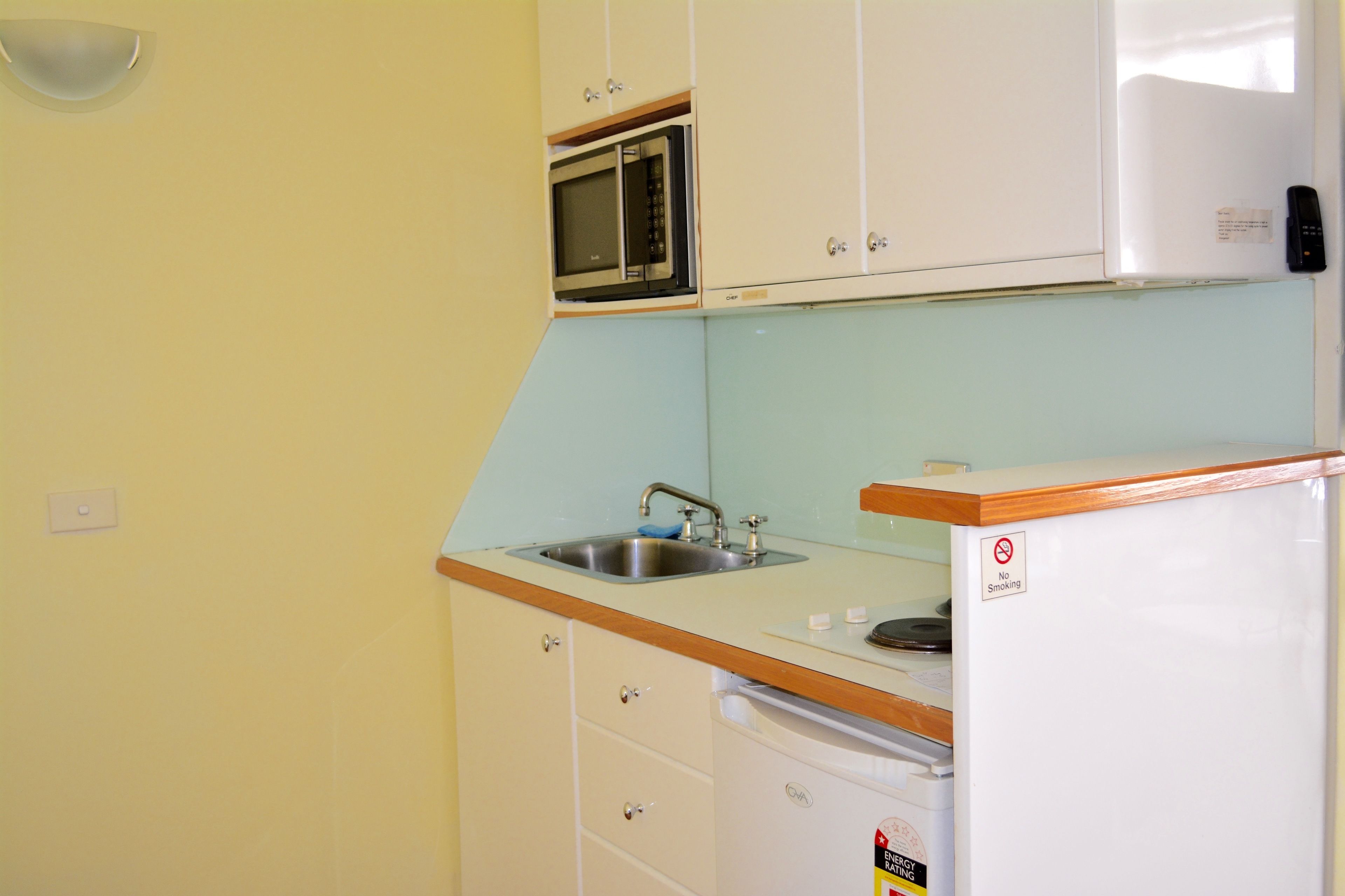 A compact kitchen with a sink, microwave, and refrigerator.
