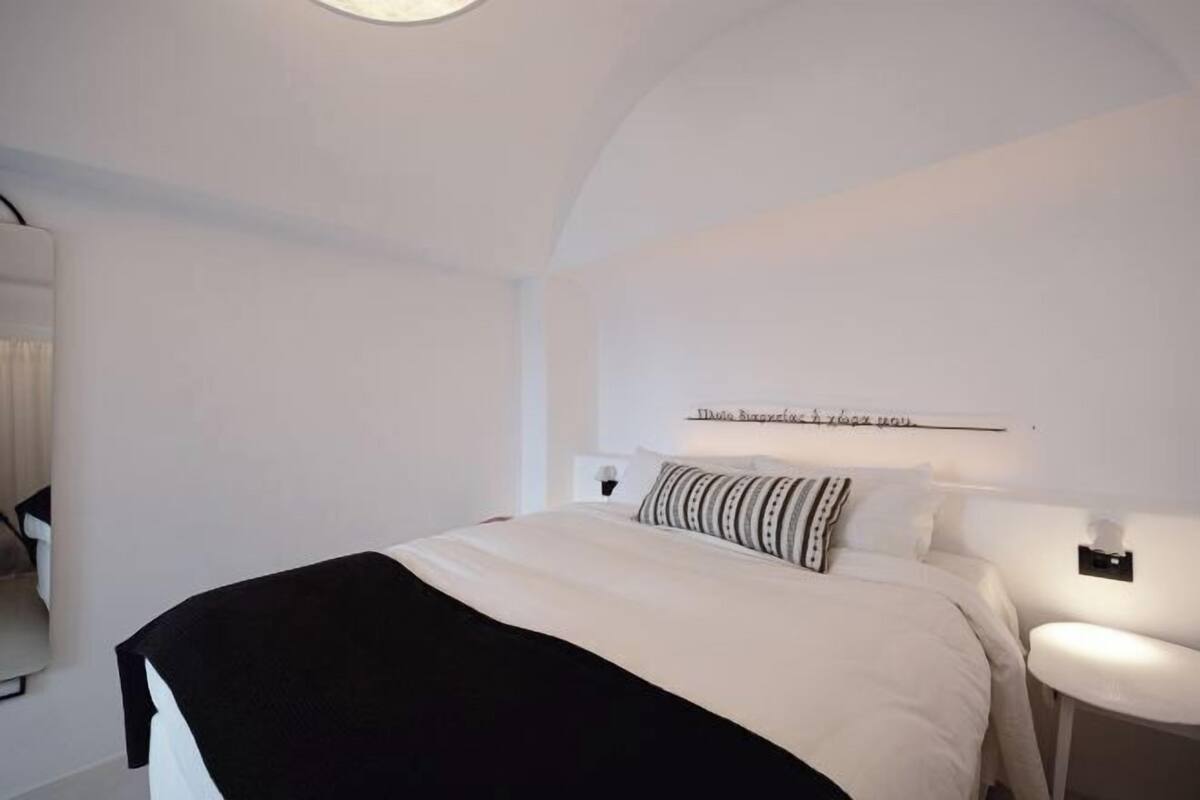 A modern bedroom with a bed, bedside tables, and a wall-mounted light fixture.