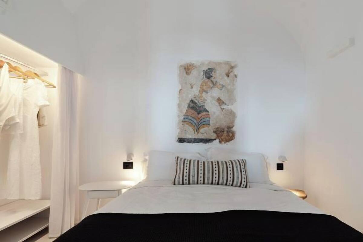 A bedroom with a bed, a wall-mounted artwork, a bedside table, and a wardrobe.
