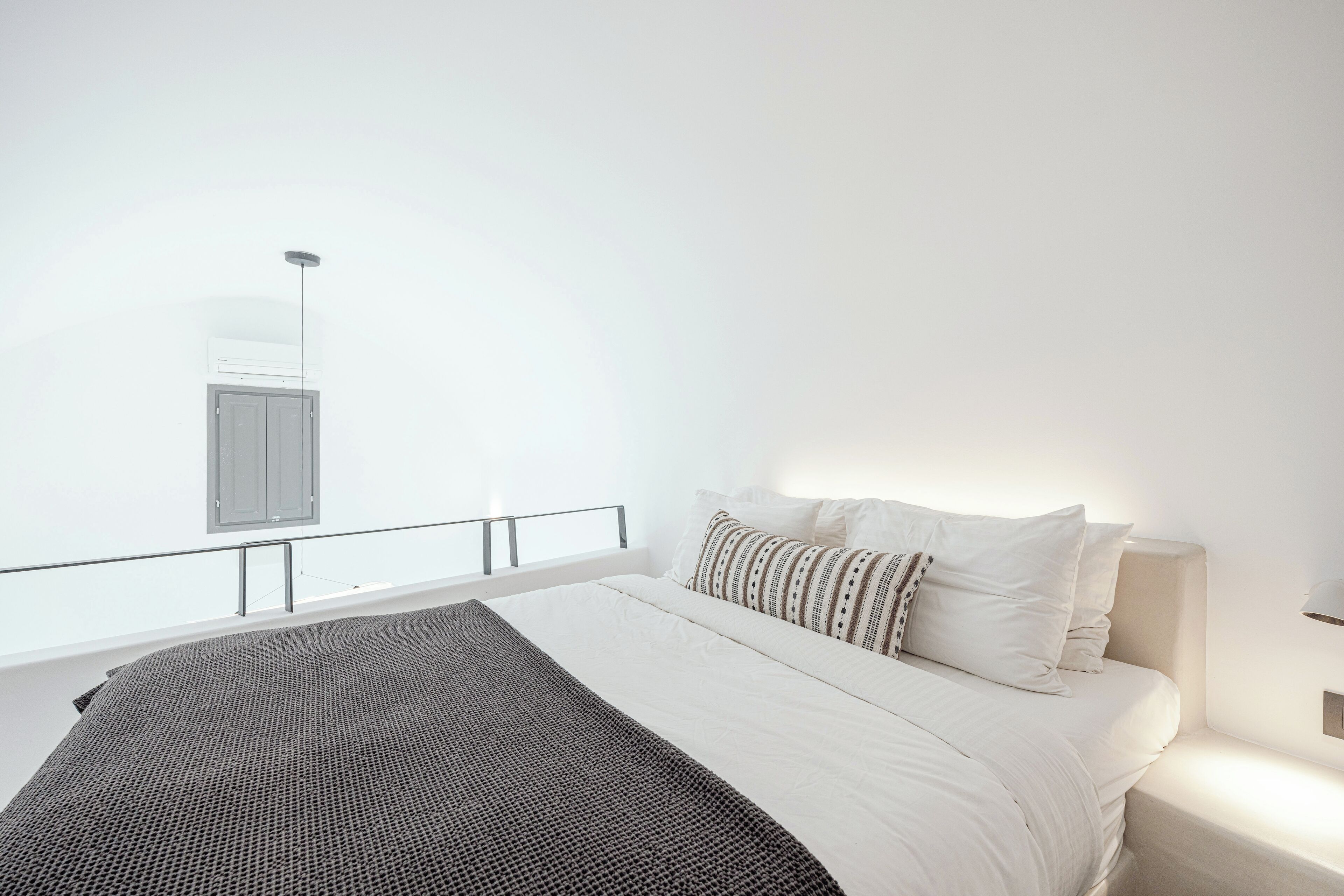 Un dormitorio moderno con una cama grande, una mesita de noche, un ventanal con vistas y un equipo de aire acondicionado instalado en el techo.