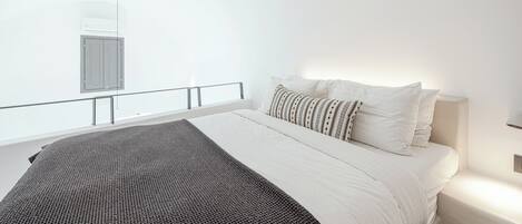 Un dormitorio moderno con una cama grande, una mesita de noche, un ventanal con vistas y un equipo de aire acondicionado instalado en el techo.