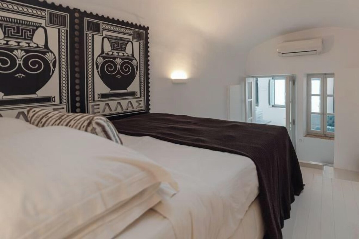 A bedroom with a bed, two wall-mounted air conditioning units, and a window with a view.