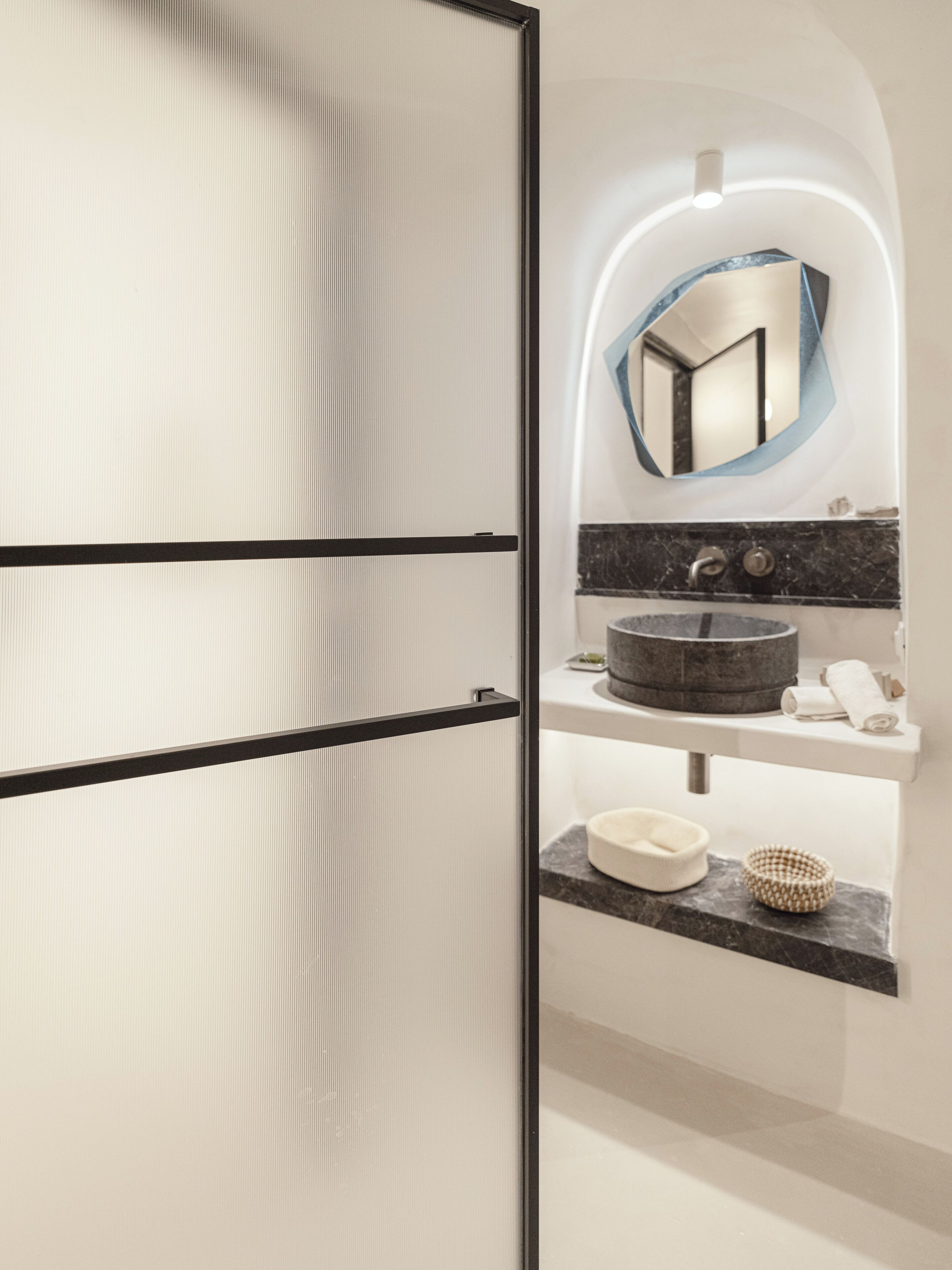 A modern bathroom with a large mirror, a round sink, and a towel rack.
