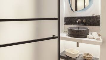 A modern bathroom with a large mirror, a round sink, and a towel rack.