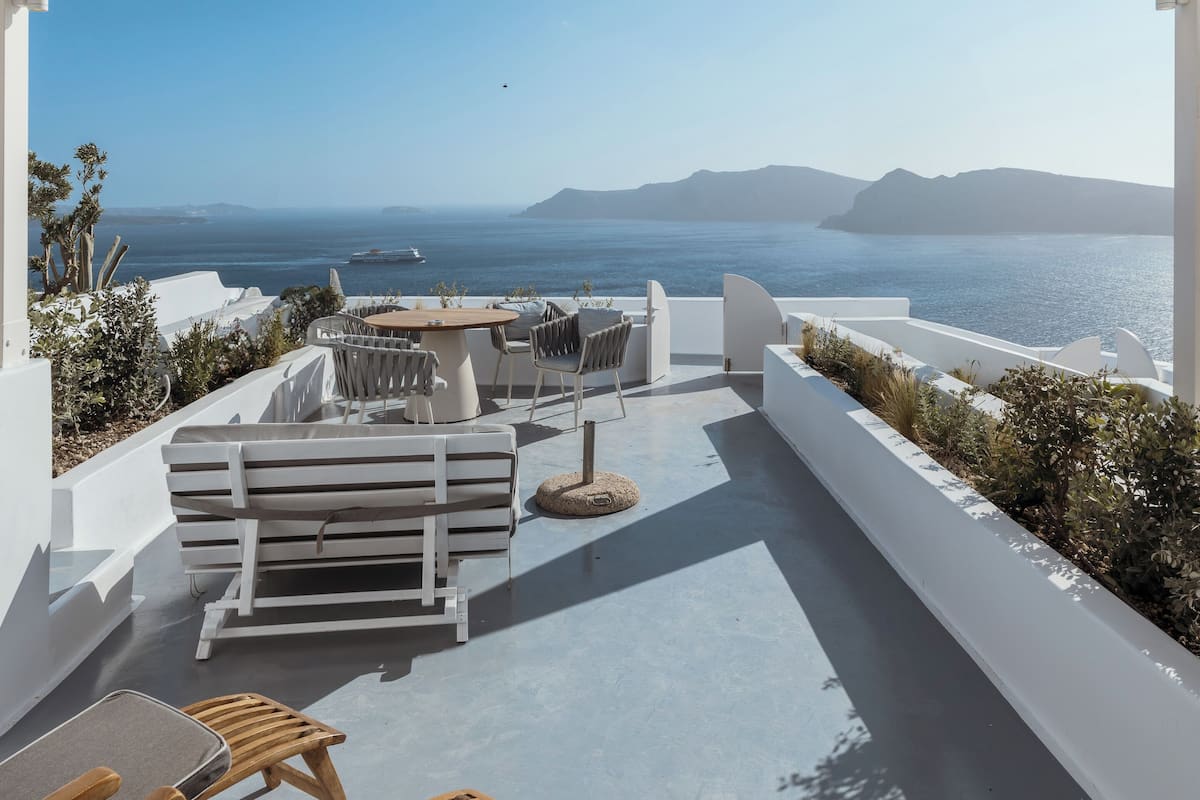 A covered outdoor seating area with a view of the sea and distant mountains.