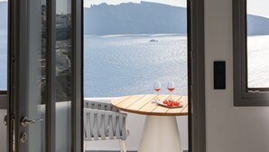 A room with a view of the sea, a table with two glasses of red wine, and a chair. - IKIES Santorini (Santorini)