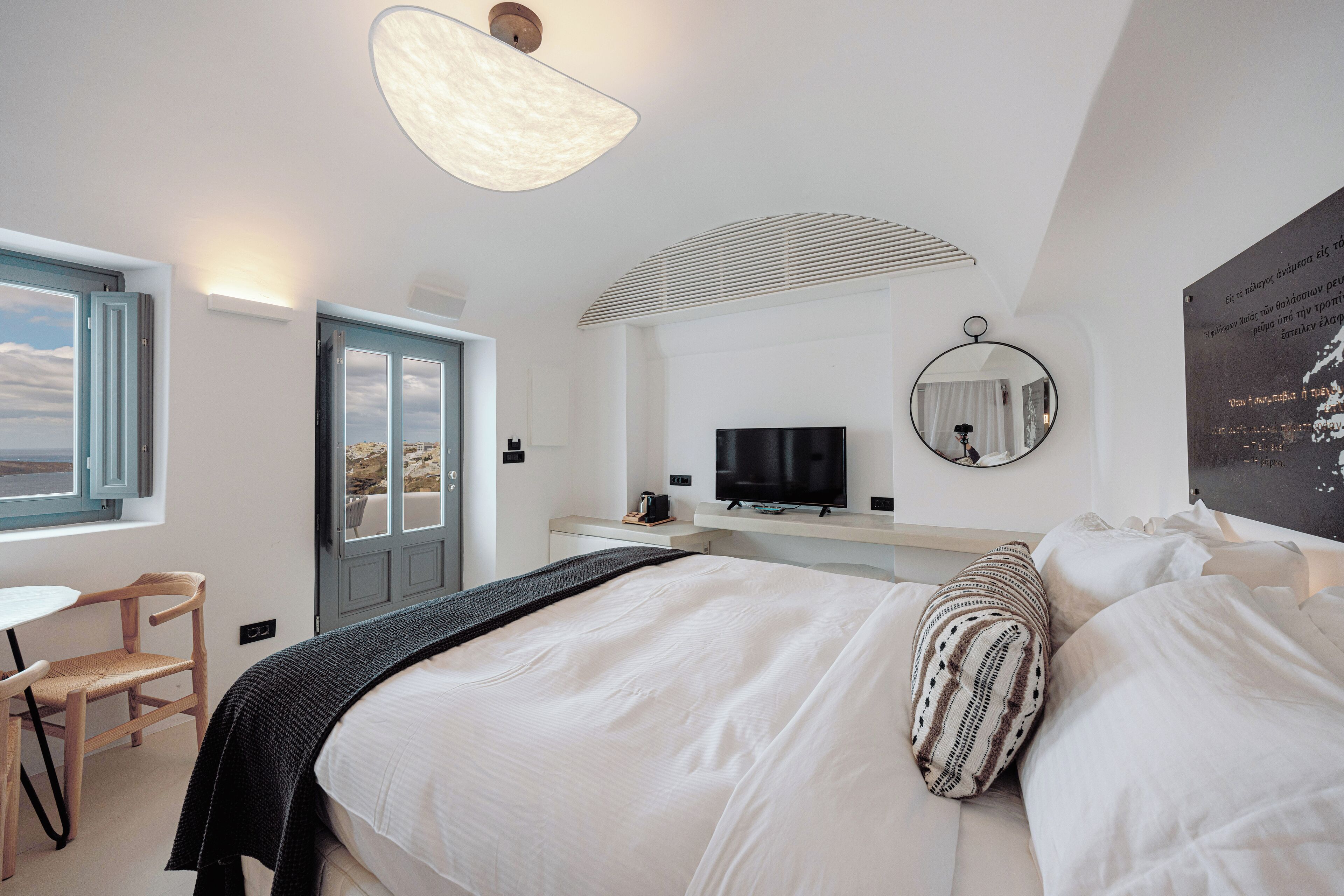 Une chambre à coucher comprenant un lit, un bureau, une chaise, un téléviseur et une fenêtre donnant sur un beau paysage.