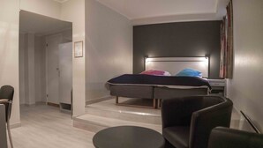 A modern hotel room with a bed, a desk, a chair, and a small table. - Melbu Hotell  (Hadsel)
