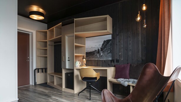A modern room with a wooden desk, a leather chair, and built-in shelving. - Melbu Hotell  (Hadsel)