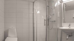 A modern bathroom with a glass-enclosed shower, a white toilet, and a sink. - Melbu Hotell  (Hadsel)