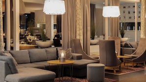 A modern living room with a sectional sofa, armchairs, a small round table, and a floor lamp. - Quality Hotel Vanersborg (Vanersborg)