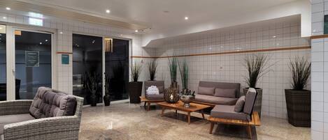Un vestíbulo moderno con área de descanso, una recepción y un muro de azulejos con una línea horizontal.