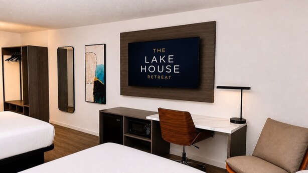 Habitación de hotel con dos camas, un escritorio con silla, televisión y espejo.