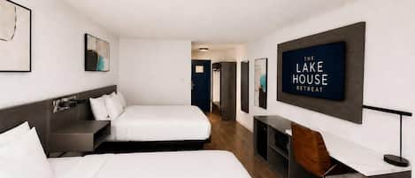 Ein Hotelzimmer mit zwei Betten, einem Schreibtisch und einem Fernseher, der 'THE LAKE HOUSE RETREAT' anzeigt.