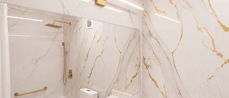 Une salle de bain moderne avec un grand miroir, une baignoire, une douche et des toilettes.