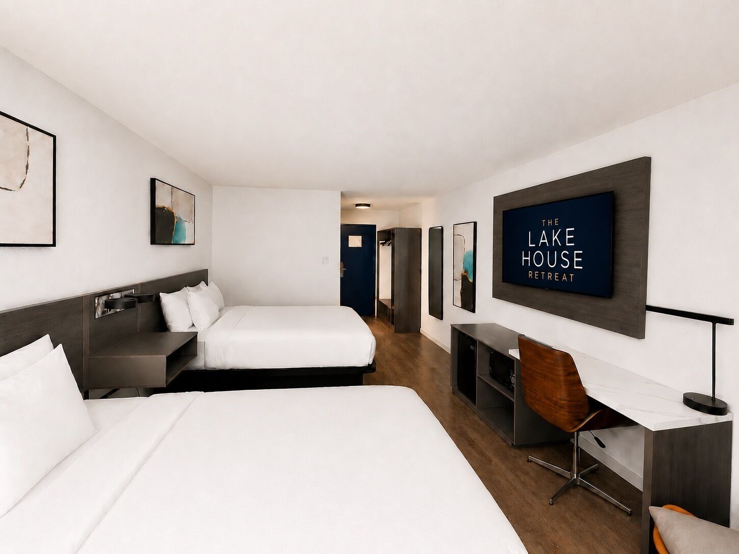 A hotel room with a bed, a desk, a chair, and a TV on the wall.