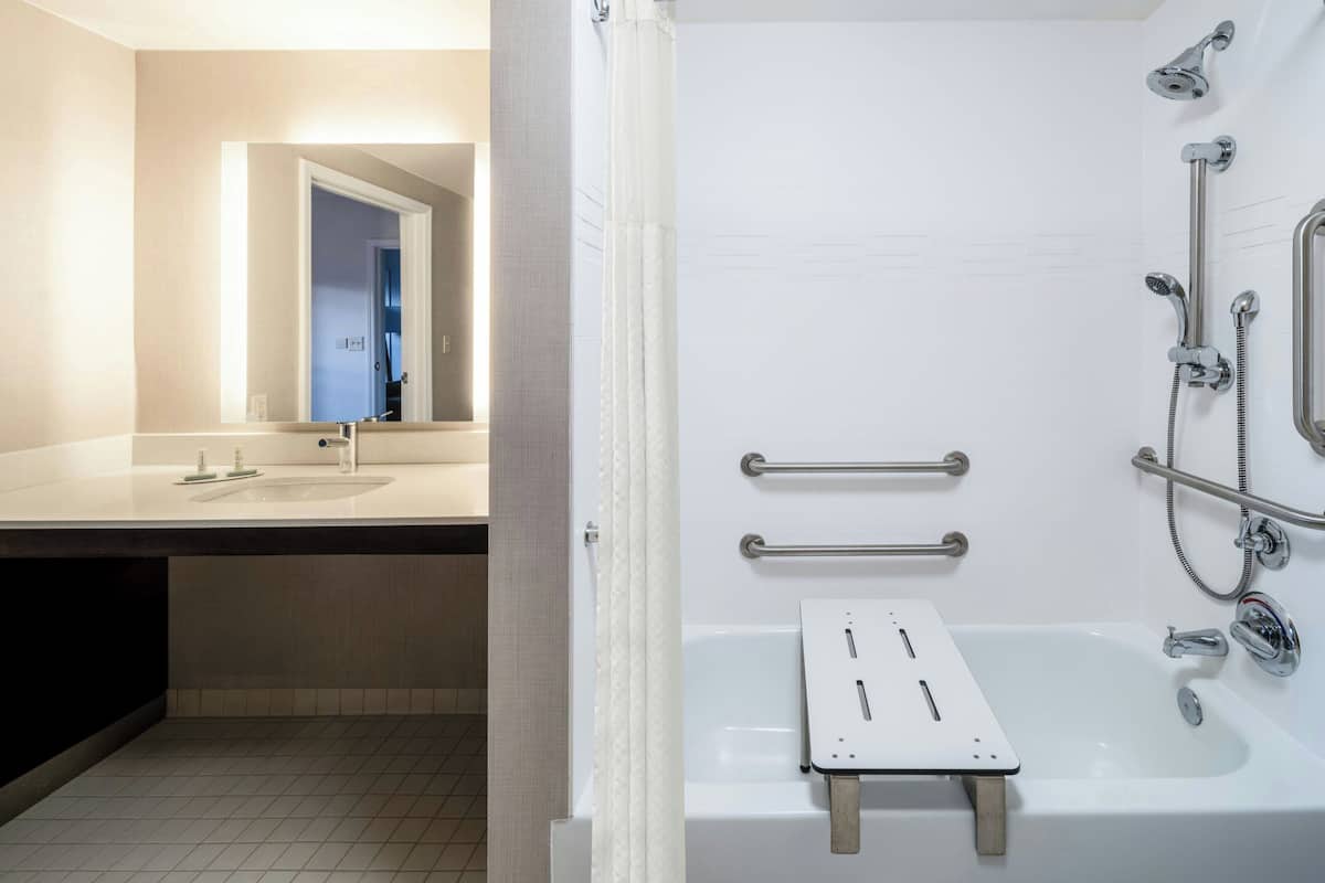 A modern bathroom with a white sink, mirror, and bathtub.