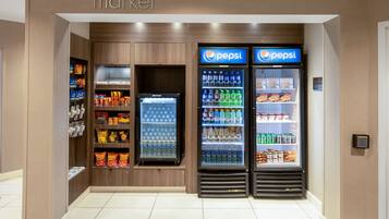 Un espace équipé de distributeurs automatiques, avec des réfrigérateurs contenant des produits Pepsi et des étagères remplies d’en-cas.
