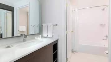Un baño moderno con un espejo grande, dos lavamanos, una bañera y una ducha.