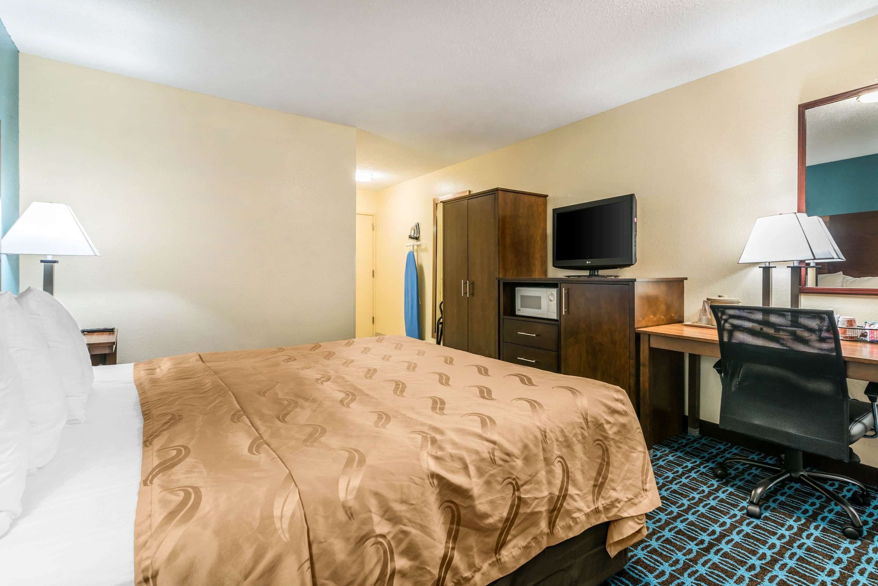 A hotel room with a bed, a desk, a television, and a wardrobe.