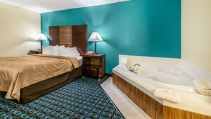 A hotel room with a bed, two bedside tables with lamps, a large bathtub, and a patterned rug. - Quality Inn Loudon-Concord (Loudon)