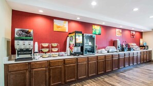 A buffet counter with various food and drink dispensers, a coffee machine, and a refrigerator. - Quality Inn Loudon-Concord (Loudon)