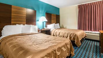 A hotel room with two beds, a nightstand, a lamp, and a window with curtains.