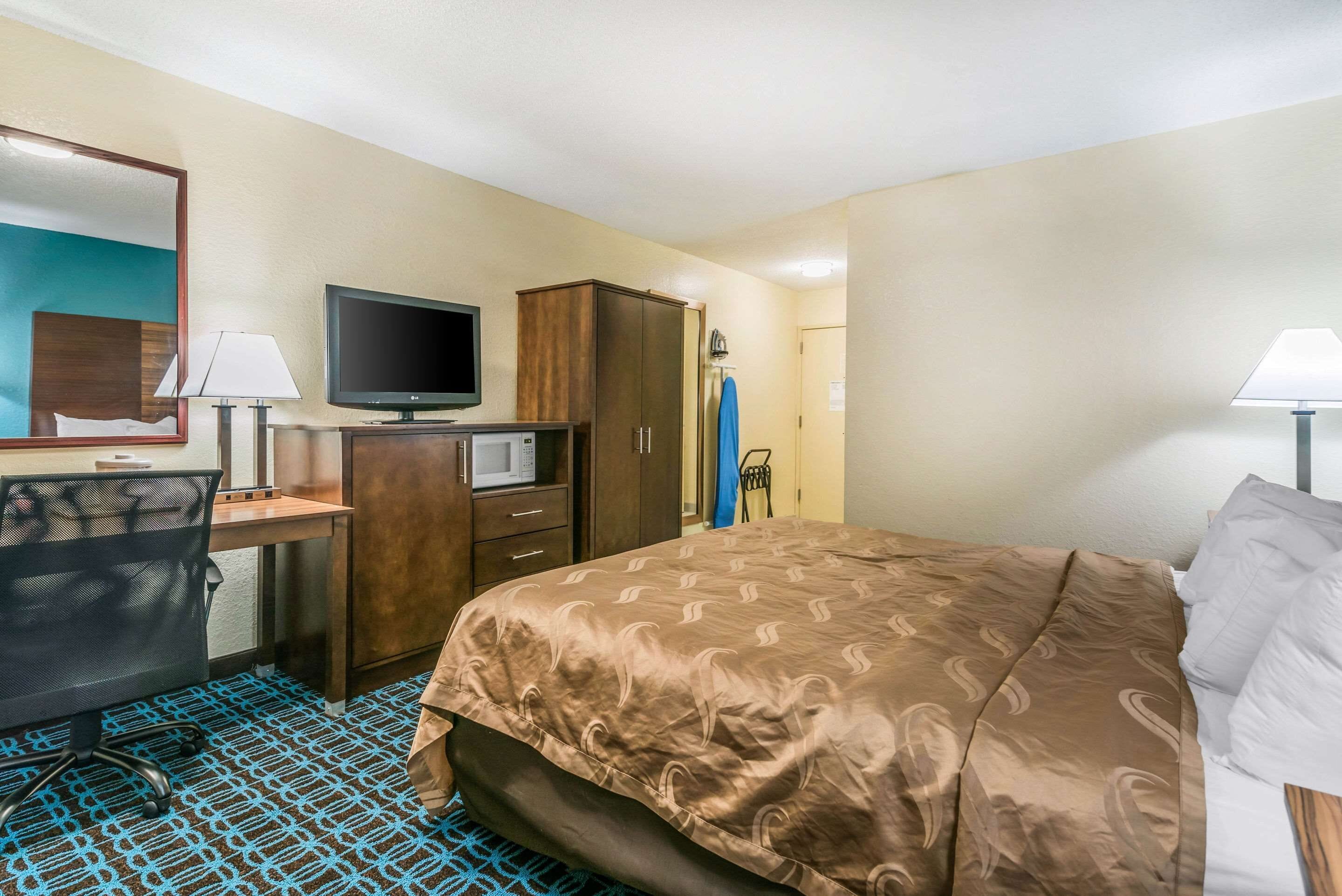 A hotel room with a bed, desk, television, wardrobe, and a bathroom visible in the background.
