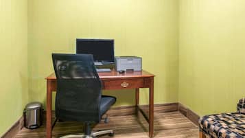 Un pequeño espacio de oficina con un escritorio, una silla, computadora, impresora y basurero.