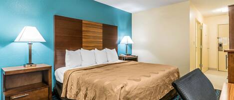 A hotel room with a bed, two bedside tables with lamps, a chair, and a desk.