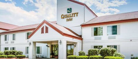 A Quality Inn hotel with a white exterior, a prominent sign, and a covered entrance.