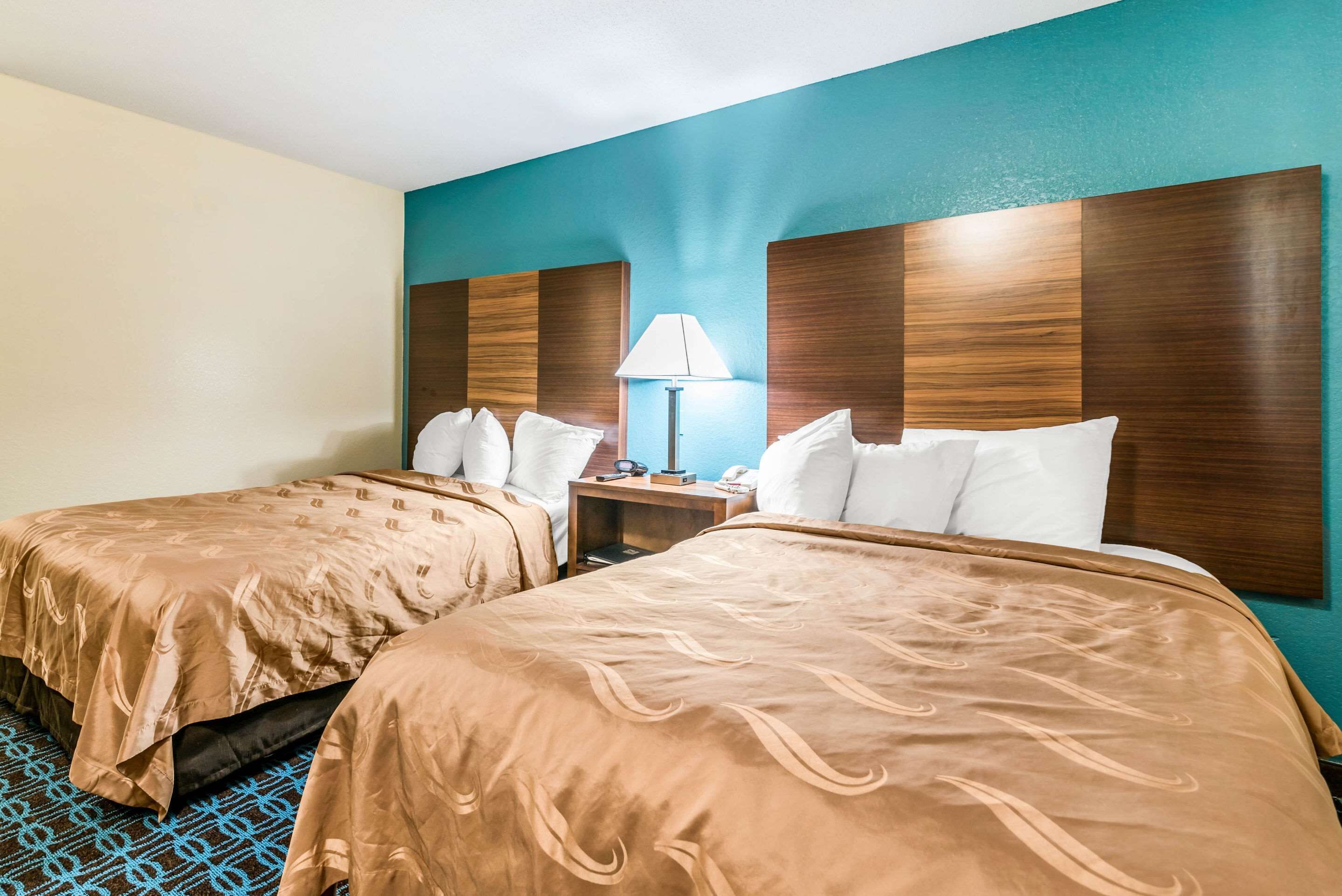 Habitación de hotel con dos camas, una mesita de noche, una lámpara y vistas al océano.