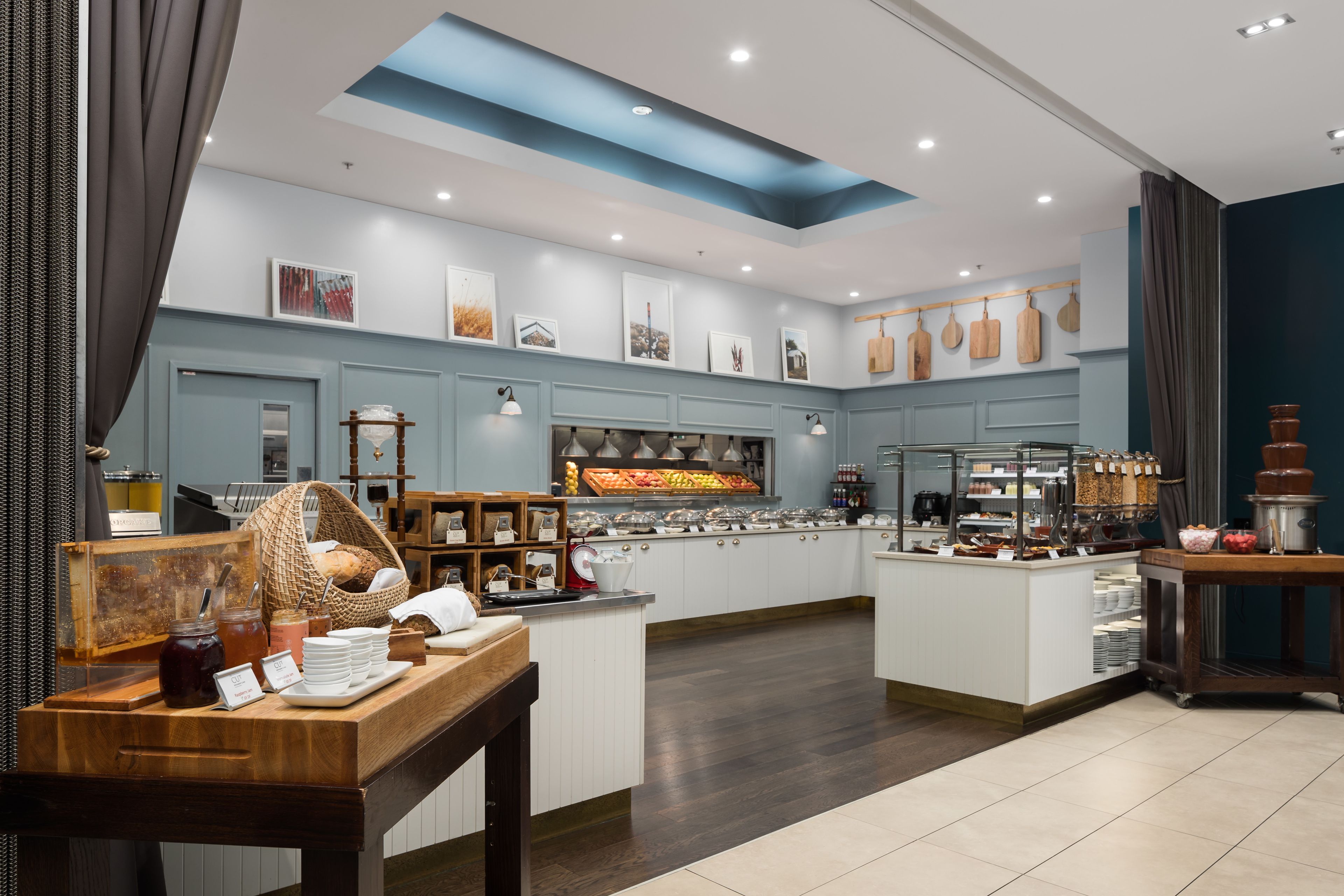 A modern breakfast bar with a variety of food options, a central island with seating, and a blue accent wall.