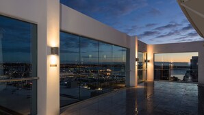 A modern building with large windows offering a view of a cityscape at dusk. - Rydges Auckland (Auckland)