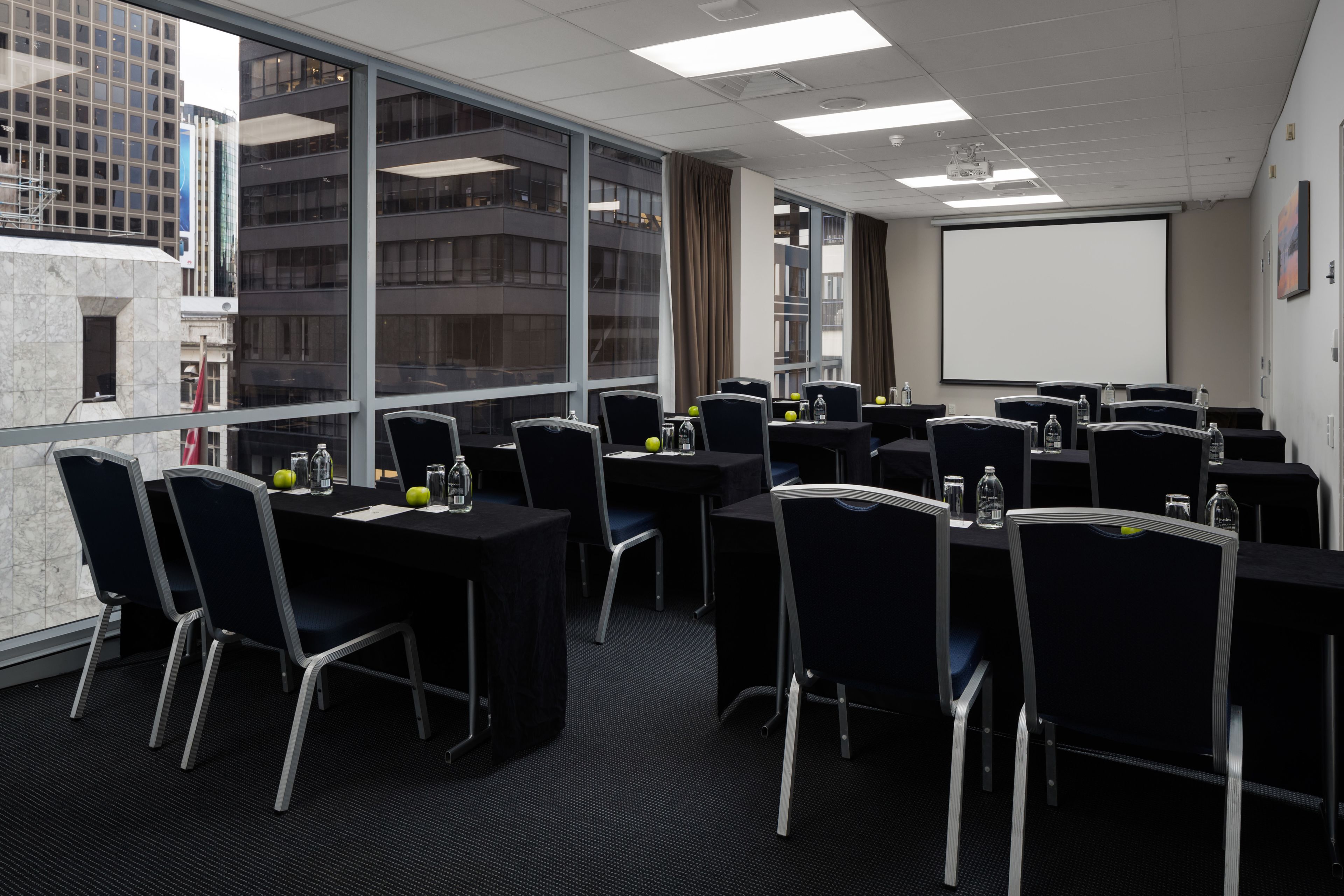 A conference room with tables, chairs, and a projector screen.