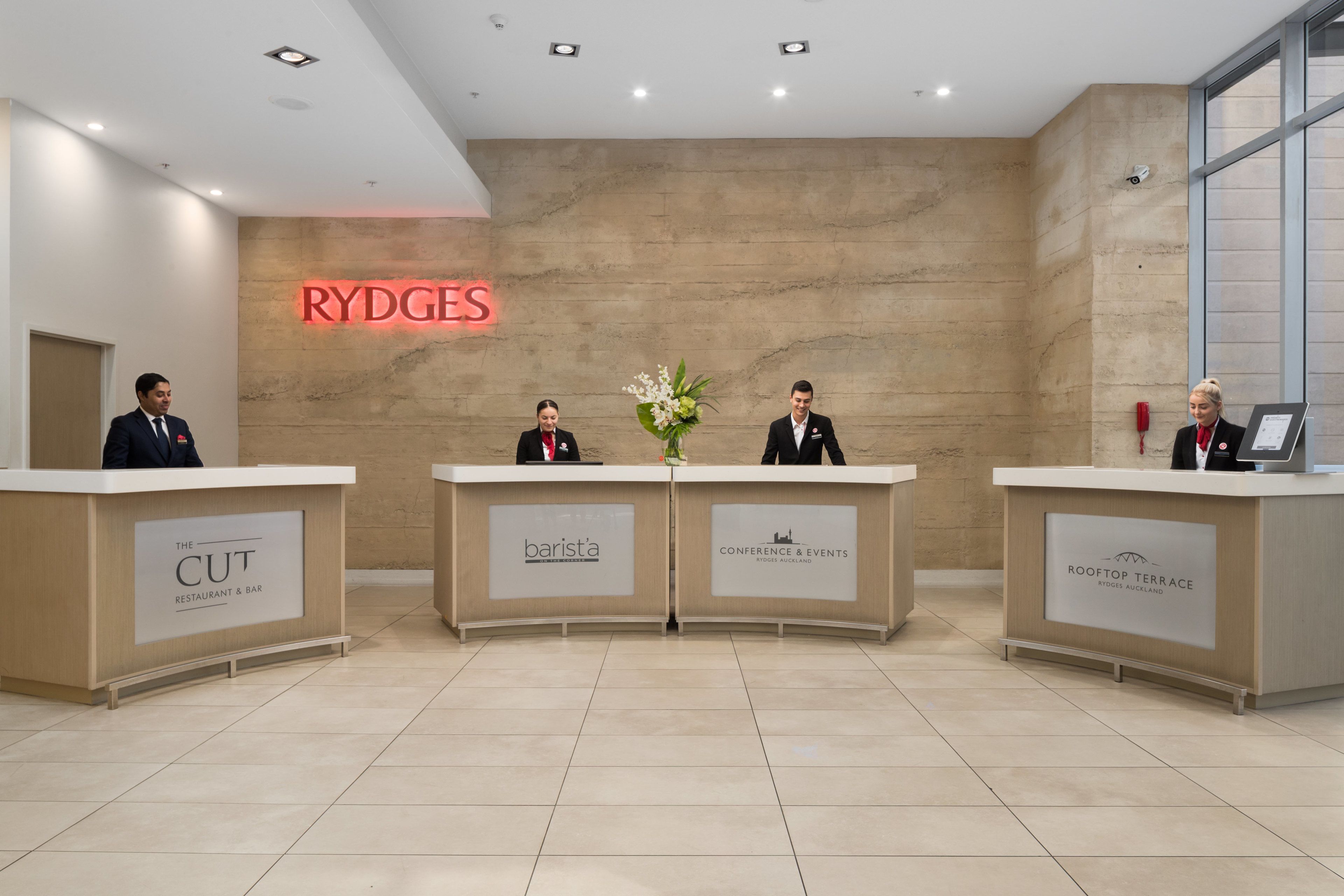 Un área de recepción con tres mostradores identificados como 'RYDGES', 'barista' y 'TERRAZA EN LA AZOTEA'.