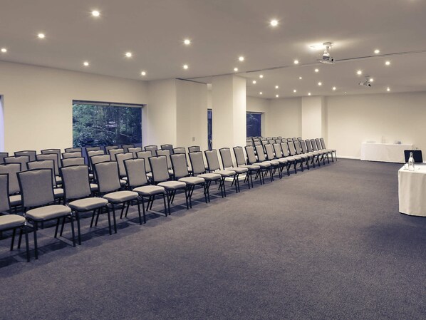 A conference room with rows of chairs, a projector, and a table with a laptop.