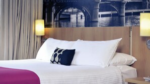 Une chambre d’hôtel avec un lit, deux lampes de chevet, un rideau et une fresque murale.